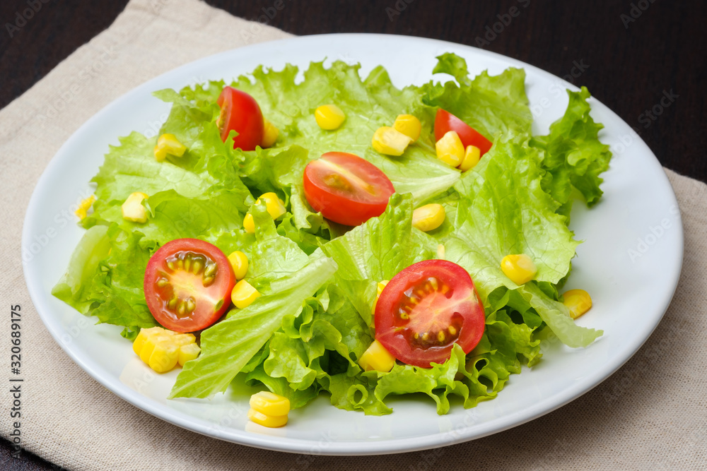 Salad of lettuce and cherry tomato,orange,corn in white dish.Concept for a tasty and healthy meal.vegetarian food concept on white background Salad of lettuce and cherry tomato,orange,corn in white dish.Concept for a tasty and healthy meal.vegetarian food concept on white background