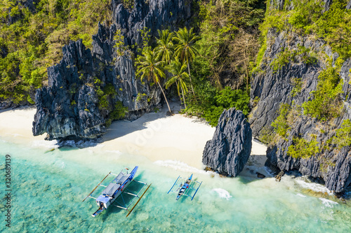 View from above, aerial view the Entalula Beach, a white sand beach surrounded by rocky formations and bathed by a crystal clear sea. Entalula island, Bacuit Bay, El Nido, Palawan, Philippines.