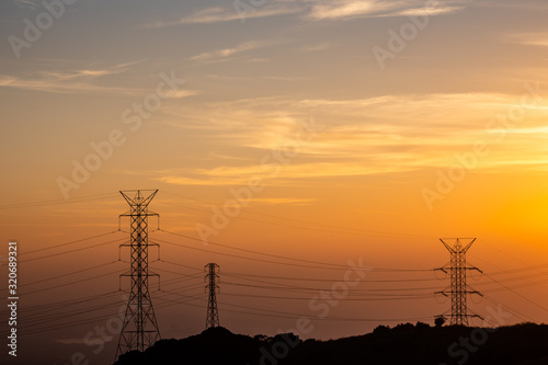 Orange sunset over power towers and lines in mountains