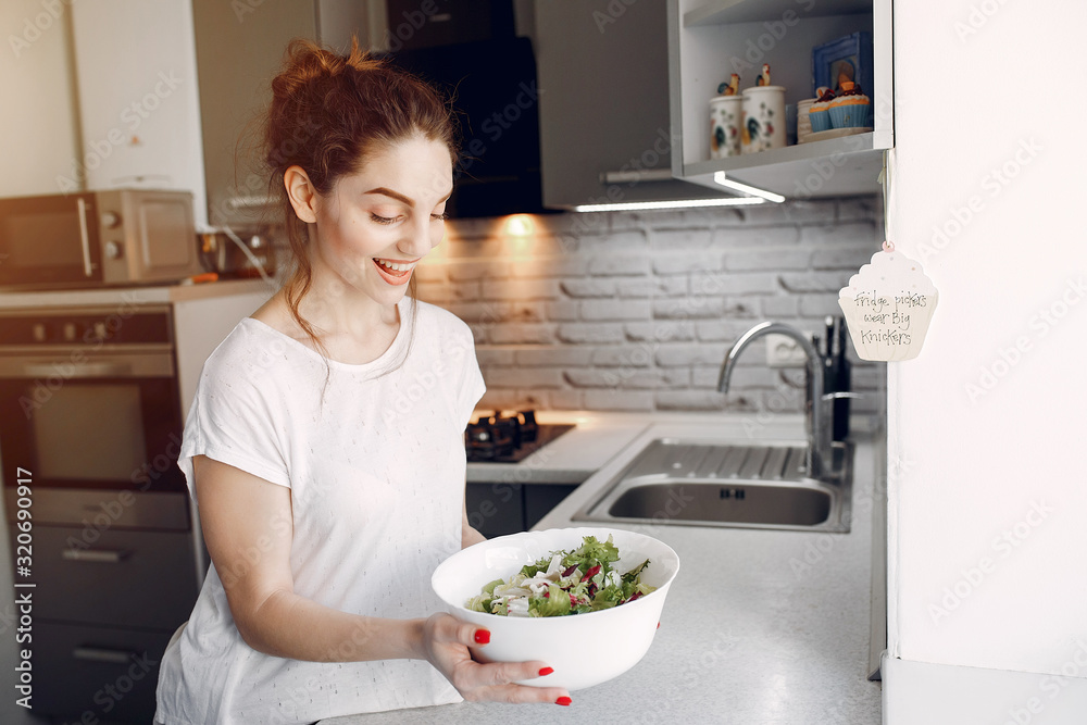 Elegant girl in a kitchen. Woman with salad. Lady in white blouse