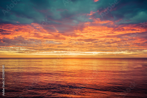 Picturesque sunrise over the sea. Dramatic sky colored in orange and red.