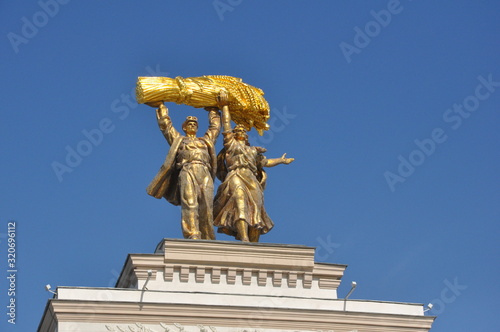 Sculpture of agricultural workers with a sheaf of cereal crops above the main entrance at VDNH in Moscow