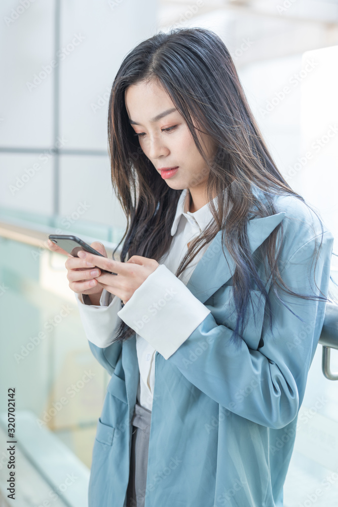Business ladies use mobile phones in the corridor of office building Business ladies use mobile phones in the corridor of office building