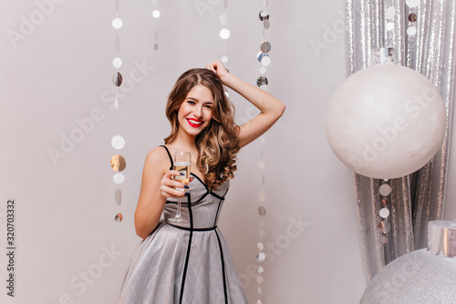 Photography Fashionable smiling girl drinking champagne near huge christmas tree toys