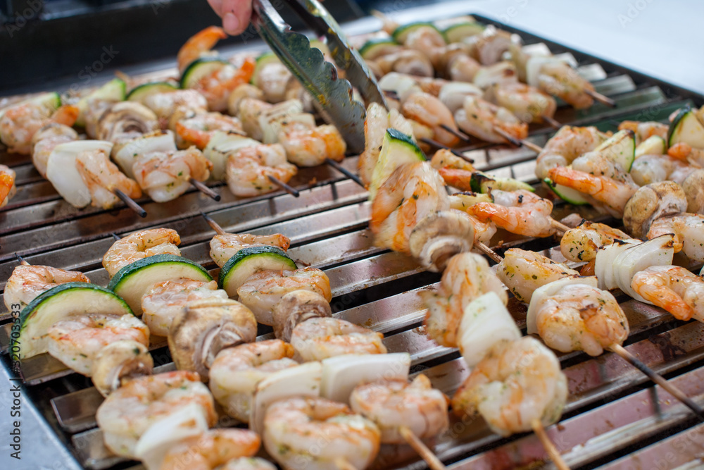 Outdoor picnic scene of seafood bbq with delicious shrimp on skews and prawn spits on a grill 