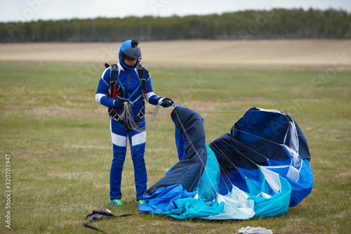 Obraz na plátně Skydiver after landing folds the canopy of a parachute close-up