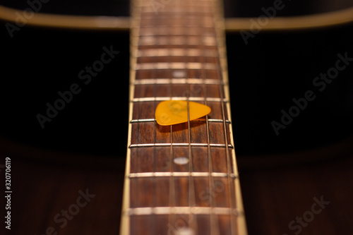 An acoustic guitar with a pick - close up on frets