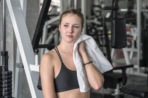 Sports tired woman after exercise wipes sweat on face in fitness gym sport club