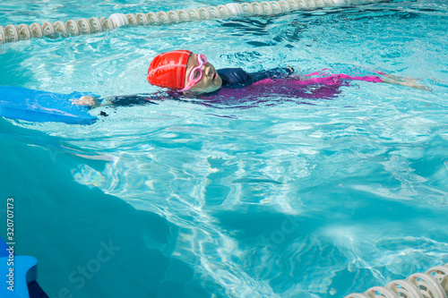 Girl kid learn how to swim in swimming class.