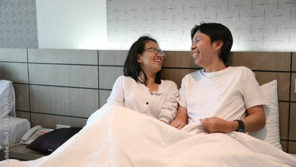 asian young couple lying in bed and laughing asian young couple lying in bed and laughing