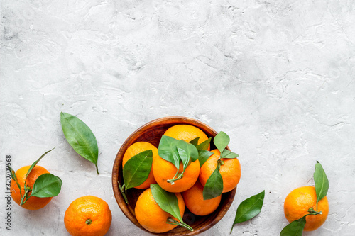 Ripe tangerines on grey table. Citruses with green leaves in bowl top-down copy space © 9dreamstudio