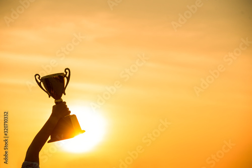 Winner win holding golden champion trophy cup prize. Silhouette best award victory trophy for professional champion challenge team holding gold sport trophy cup over head. Win-Win sport team concept photo