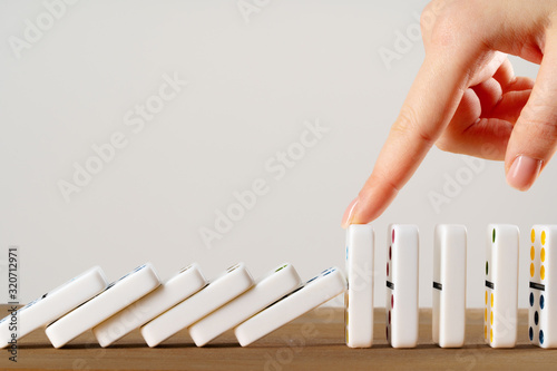 Woman hand toppling dominoes. Chain reaction business concept