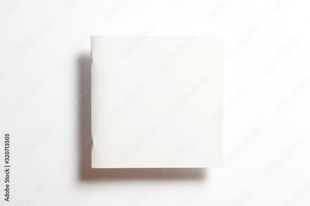 Blank glossy portrait paper square catalog magazine in the air isolated on white with soft shadows Blank glossy portrait paper square catalog magazine in the air isolated on white with soft shadows