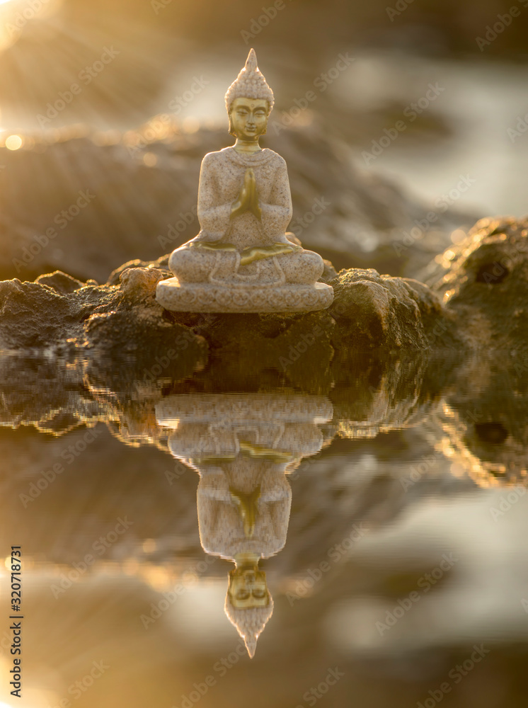 A buddha on the rocks and its reflection in the water