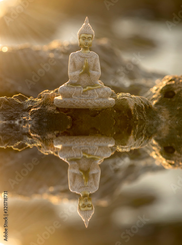 Obraz na płótnie A buddha on the rocks and its reflection in the water w salonie