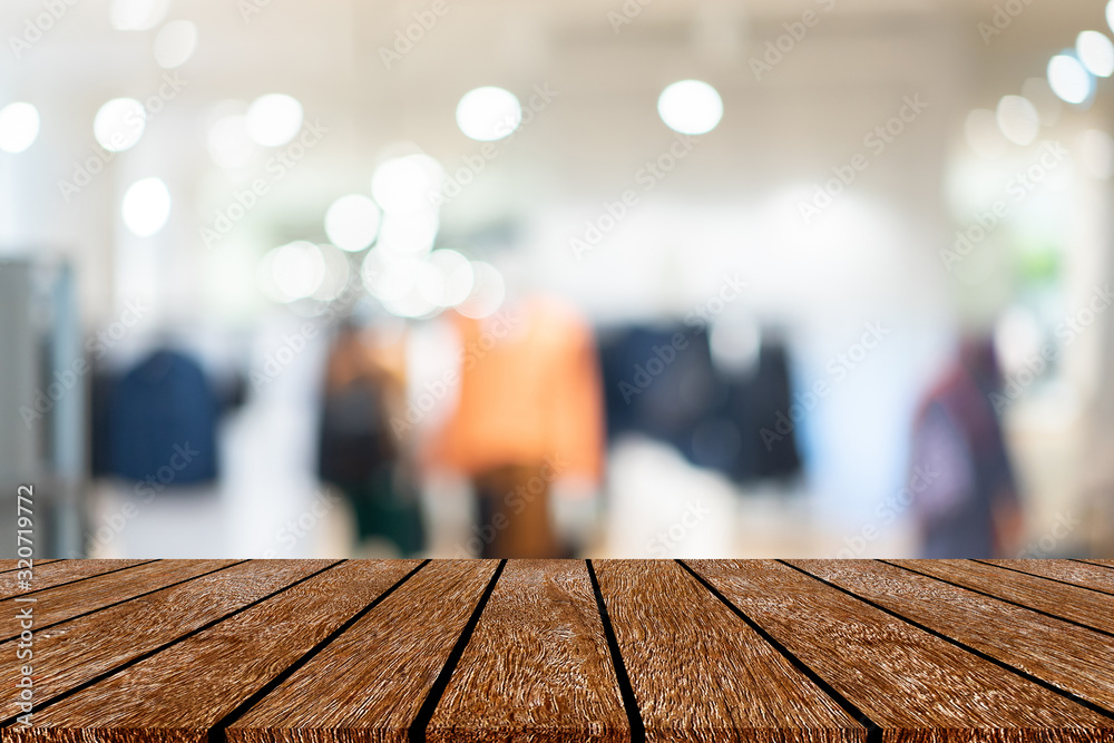 abstract blur clothing store inside shopping mall with wood tabletop for show , promote  promotion on display concept