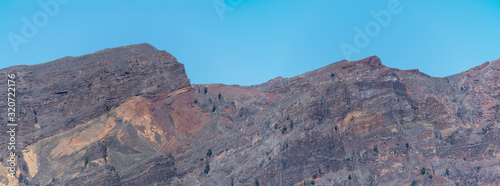 Panoramic view on colorful vocanic rock of crater Caldera de Taburiente with mountainRoque de los Muchachos on the island La Palma, Canary Islands, Spain. Blue sky background