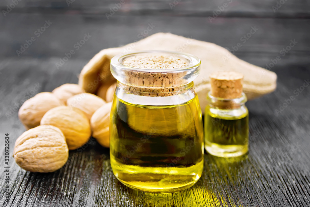Oil walnut in jar and bottle on board Oil walnut in jar and bottle on board