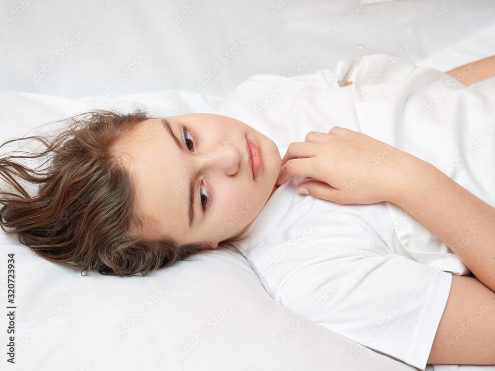 sick girl lying in white bed with a thermometer. . coronavirus