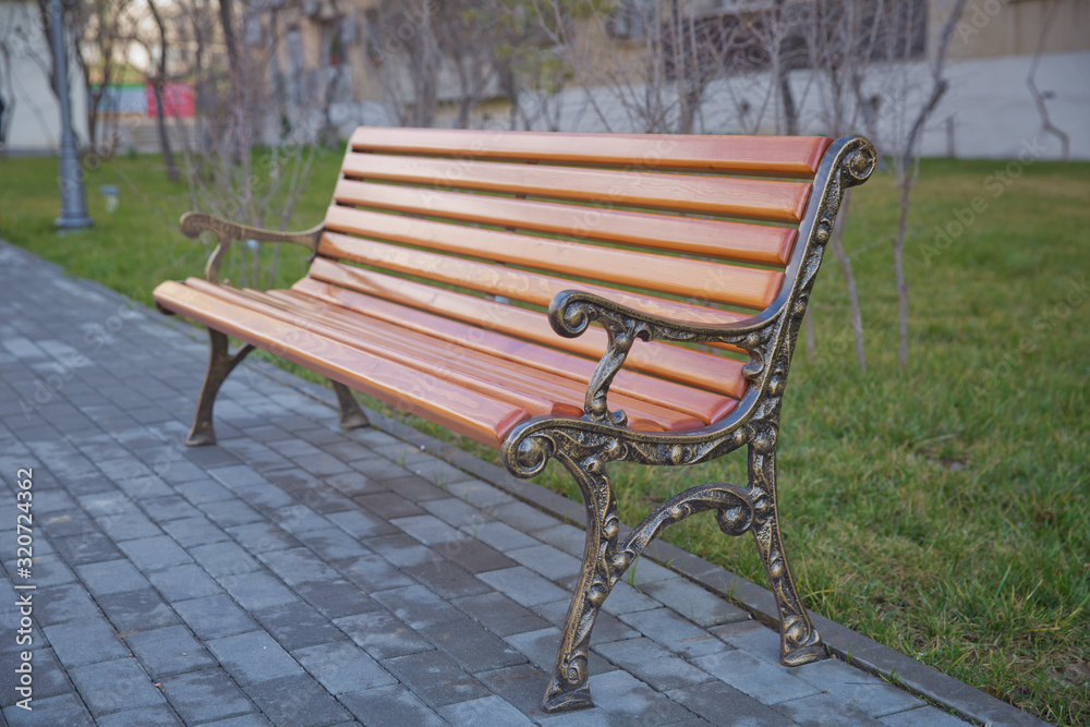 Wood exterior material. Wood material details. Blank Old bench in a shady area of the garden or the park,outdoor. Shaded wood park bench surrounded by greenery . Empty Park wooden bench Closeup view. Wood exterior material. Wood material details. Blank Old bench in a shady area of the garden or the park,outdoor. Shaded wood park bench surrounded by greenery . Empty Park wooden bench Closeup view.