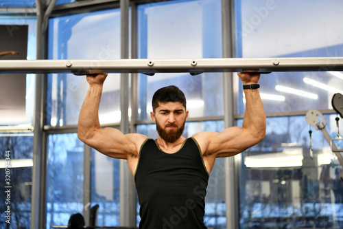 male athlete doing physical exercises for the development of the body in the gym