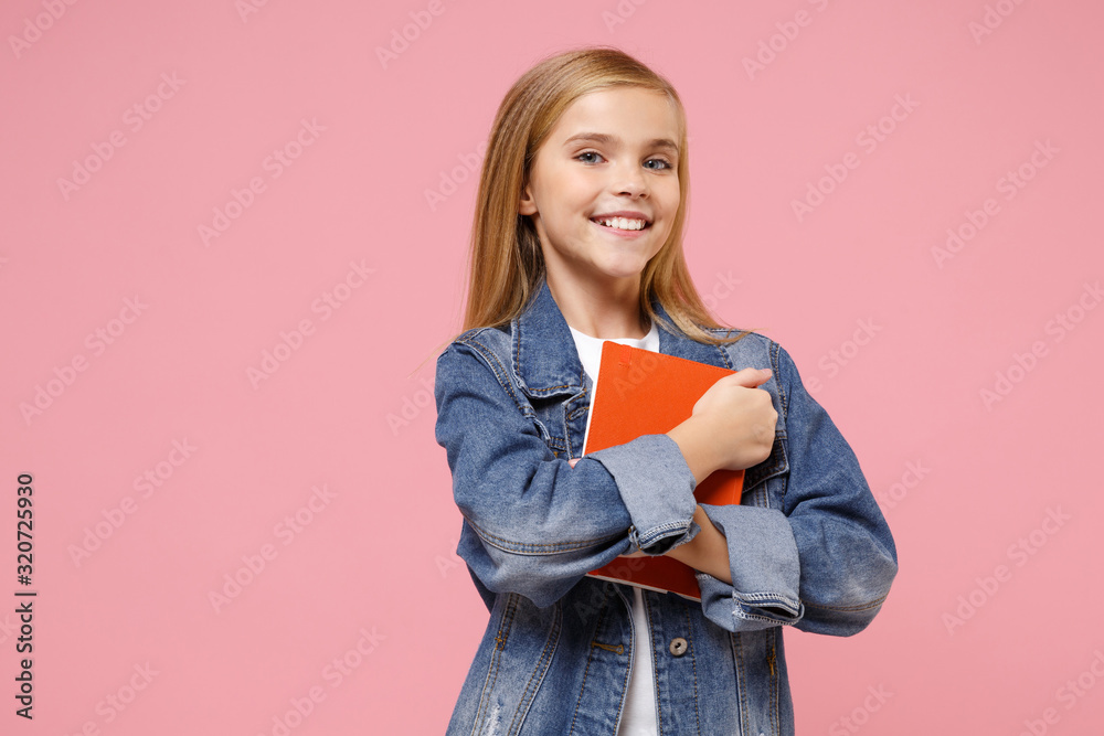 Smiling little blonde kid girl 12-13 years old in denim jacket isolated on pastel pink background children studio portrait. Childhood lifestyle concept. Mock up copy space. Holding book, notebook. Smiling little blonde kid girl 12-13 years old in denim jacket isolated on pastel pink background children studio portrait. Childhood lifestyle concept. Mock up copy space. Holding book, notebook.
