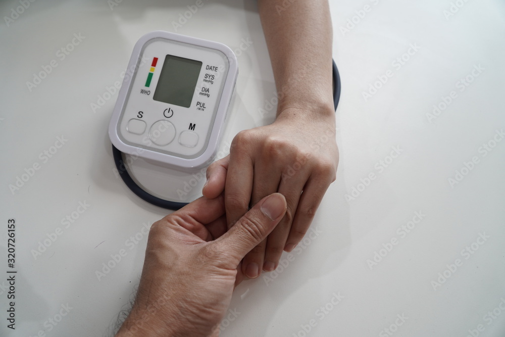 Monitoring blood pressure of patients using upper arm blood pressure monitor in the clinic examination room. Monitoring blood pressure of patients using upper arm blood pressure monitor in the clinic examination room.