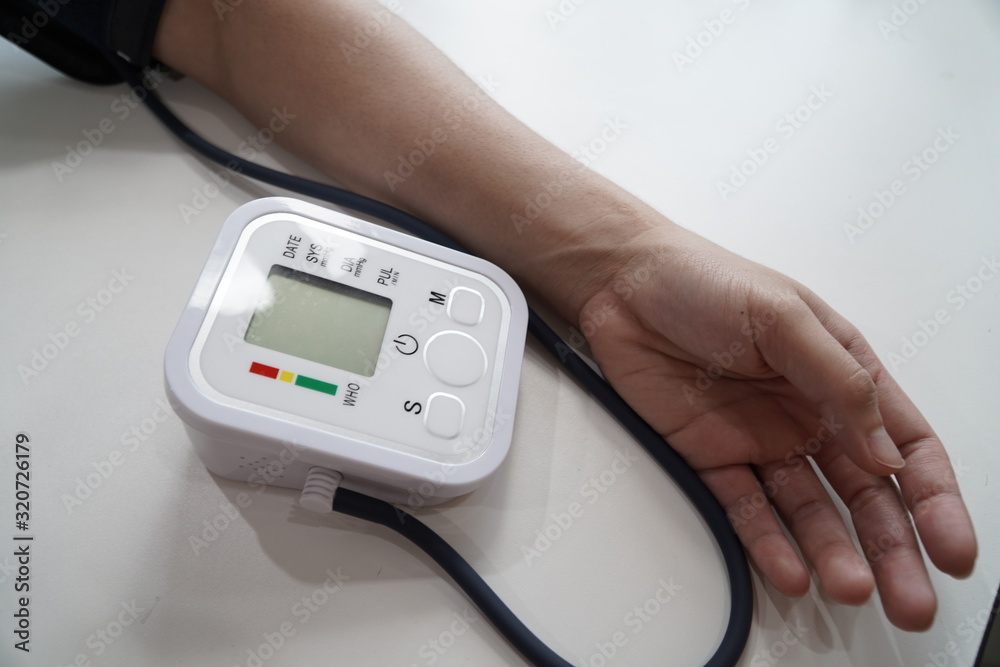 Monitoring blood pressure of patients using upper arm blood pressure monitor in the clinic examination room. Monitoring blood pressure of patients using upper arm blood pressure monitor in the clinic examination room.