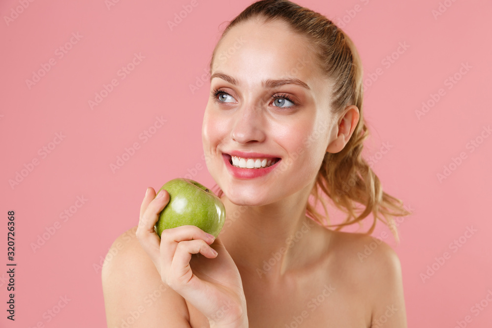 Close up blonde half naked woman 20s perfect skin nude make up hold apple isolated on pastel pink wall background studio portrait. Skin care healthcare cosmetic procedures concept. Mock up copy space. Close up blonde half naked woman 20s perfect skin nude make up hold apple isolated on pastel pink wall background studio portrait. Skin care healthcare cosmetic procedures concept. Mock up copy space.