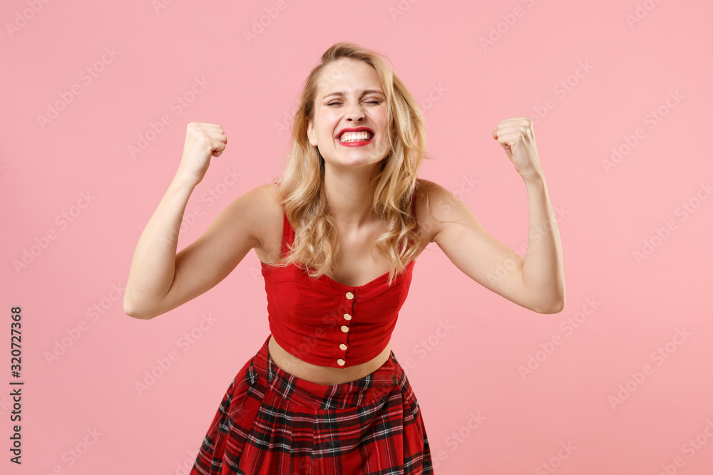 Joyful young blonde woman girl in red sexy clothes posing isolated on pastel pink background studio portrait. People lifestyle concept. Mock up copy space. Doing winner gesture, keeping eyes closed. Joyful young blonde woman girl in red sexy clothes posing isolated on pastel pink background studio portrait. People lifestyle concept. Mock up copy space. Doing winner gesture, keeping eyes closed.