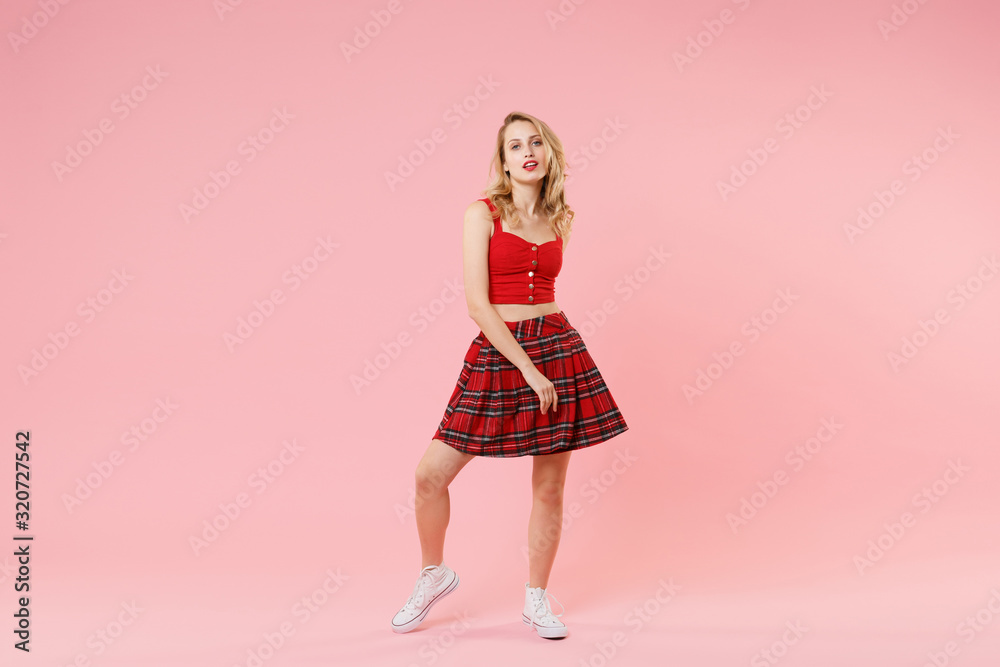 Attractive young blonde woman girl in red sexy clothes posing isolated on pastel pink wall background studio portrait. People sincere emotions lifestyle concept. Mock up copy space. Looking camera. Attractive young blonde woman girl in red sexy clothes posing isolated on pastel pink wall background studio portrait. People sincere emotions lifestyle concept. Mock up copy space. Looking camera.
