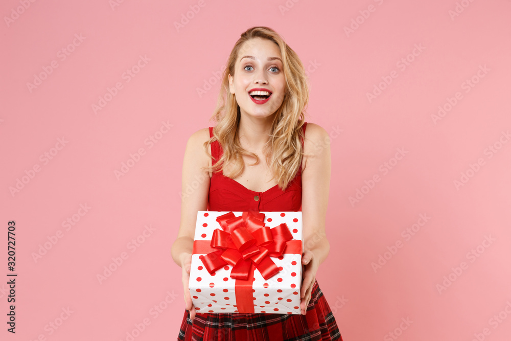 Cheerful young woman in red sexy clothes isolated on pastel pink background. St. Valentine's Day, International Women's Day, birthday, holiday concept. Hold red white present box with gift ribbon bow. Cheerful young woman in red sexy clothes isolated on pastel pink background. St. Valentine's Day, International Women's Day, birthday, holiday concept. Hold red white present box with gift ribbon bow.