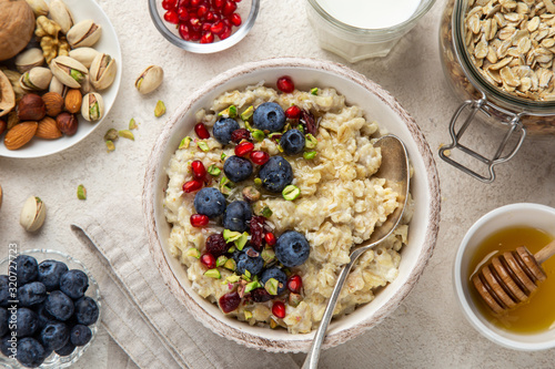 Oatmeal porridge with fresh berry, nuts and honey in bowl