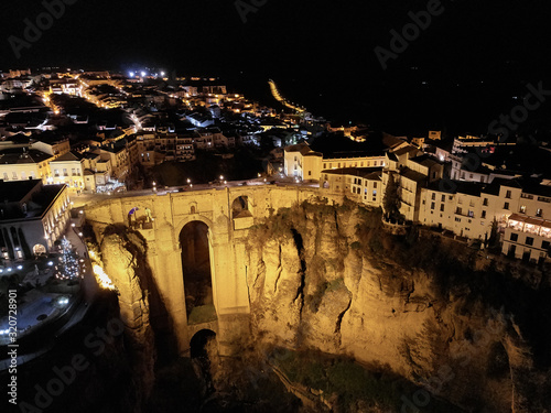 Aerial photo drone point of view huge gorge and ancient architecture, city street lights night view of Ronda in Spanish province of Málaga. Costa Blanca. Spain