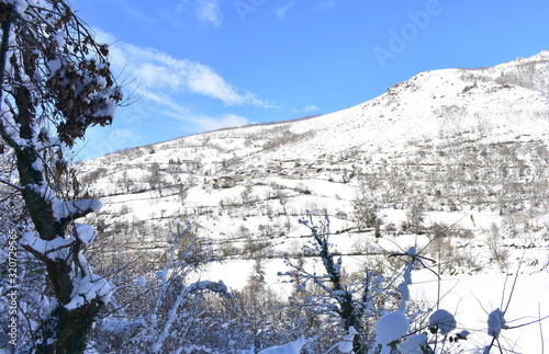 Winter landscape with small mountain village on a snowy slope with blue sky. Ancares, Lugo, Galicia, Spain.