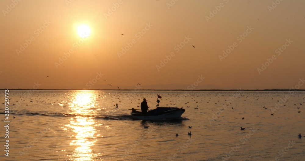 Silhouette of fisherman in a boat on the Beautiful sunset on the sea.