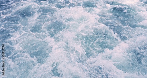 Close up powerful waves pulled out from boat. Water foam trace behind the ship.