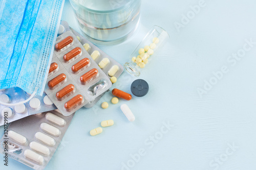 Top view of assorted medicine pills and tablets, glass of water.