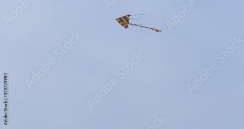 Colorful kite flying in blue sky. Toy for fun and leisure activity. Recreation.