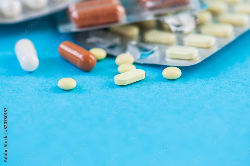 Close up of assorted medicine pills and tablets on a blue background.