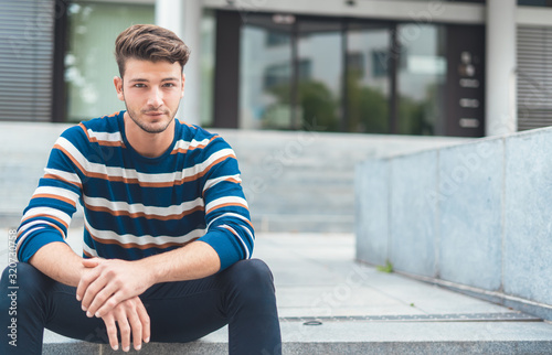 Handsome young man sitting on stairs