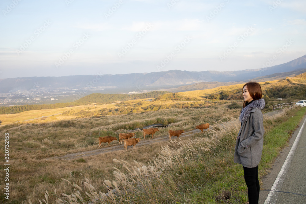 Fototapeta premium Lonely girl in Area of Aso active volcano background with smoke at Mount Aso Nakadake, Kumamoto, kyushu, Japan. (Photo grain some noise on film colour)