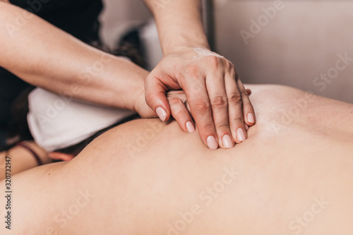 Strong female hands of a masseur during a back massage
