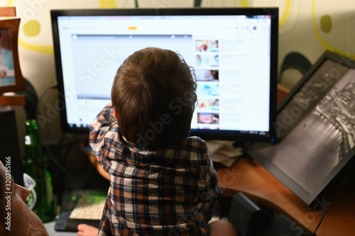 Little baby behind a computer monitor. Back view