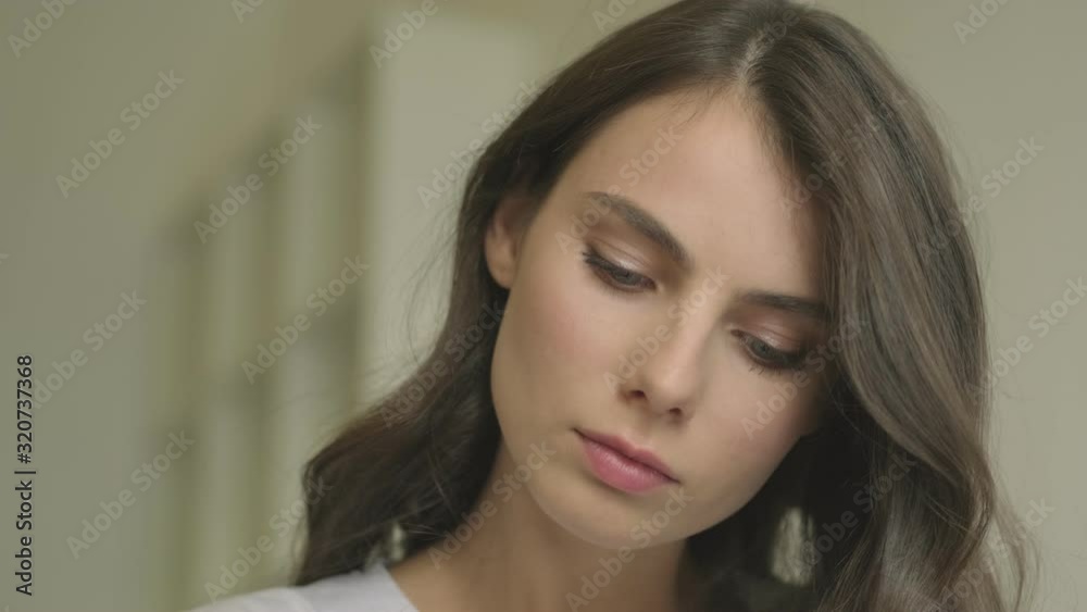 A focused beautiful young woman is writing something while sitting at the table in the cafe indoors A focused beautiful young woman is writing something while sitting at the table in the cafe indoors