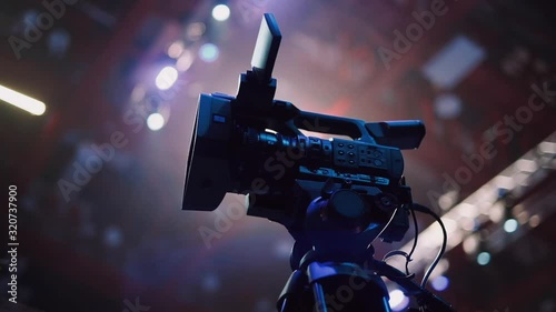 A professional video camera stands on a tripod before the start of the big event