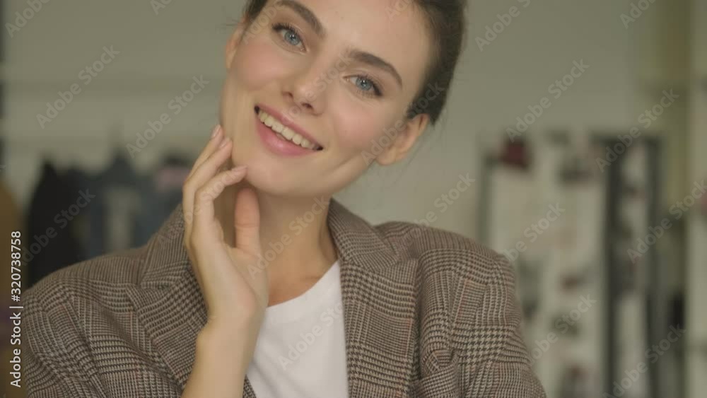A pretty calm young woman is looking to the camera with smile indoors in the white office A pretty calm young woman is looking to the camera with smile indoors in the white office