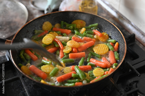 Vegetables are cooked in a pan. Cooking a hot salad on the fire. Vegetarian food at home.