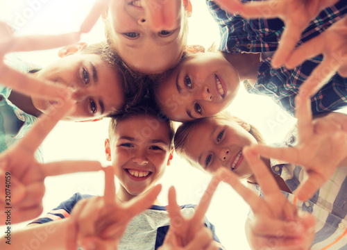 childhood, leisure, friendship and people concept - group of smiling happy children showing v sign in circle